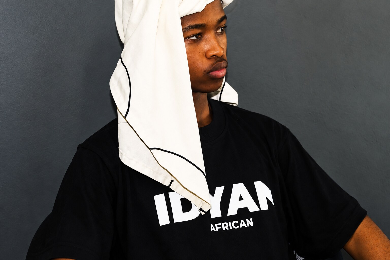 Young man wearing a black IDYAN. African tee and white headwrap