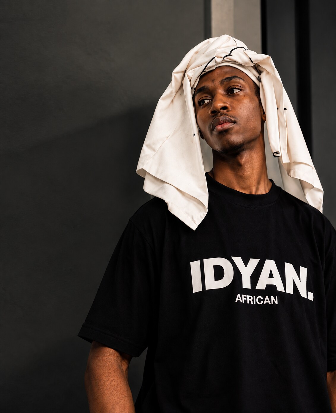 Man in a black IDYAN. African tee with a white headwrap