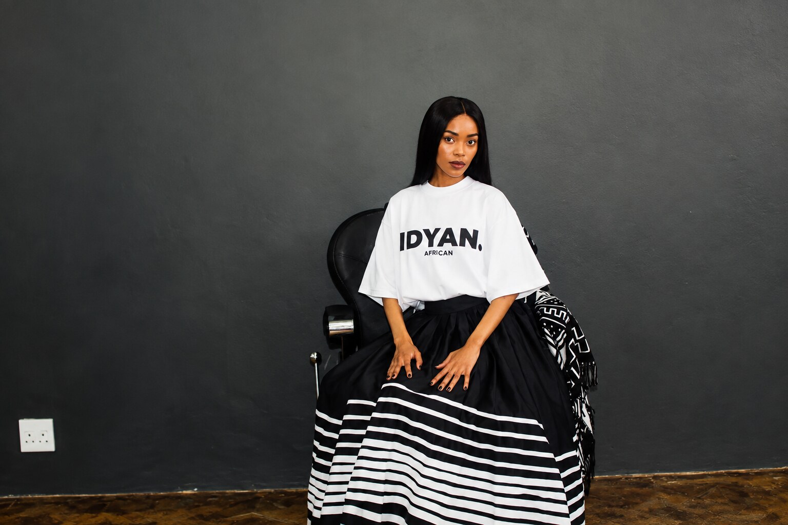 Model wearing the white OG Retro Tee in the IDYAN chair